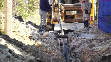 Plastic pipes laid in trenches. Workers are installing water pipeline under a city street in a trench. New pipeline in a process of building, under construction. Workers are laying pipeline. Close up video