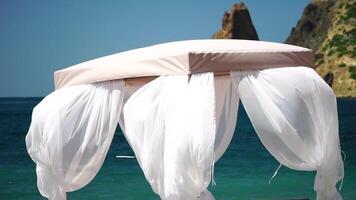 bangalôs mar. de praia salão cama com branco sedoso cortinas. salão cama com marquise às à beira-mar. de praia cadeiras e guarda-sóis. verão período de férias recorrer conceito. video