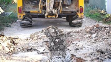 Excavator digs a trench to lay pipes. Close up of an excavator digging a deep trench. An excavator digs a trench in the countryside to lay a water pipe. Slow motion video