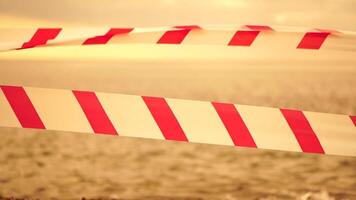 Red white warning tape barrier ribbon swinging in the wind across exotic sea beach background without people. No entry Red White caution tape. No holiday concept, delayed travel, no summer plans video