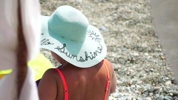 oigenkännlig positiv kvinna i bikini solbad eller garvning på havet strand under sommar. långsam rörelse av Lycklig turist njuter Sol solbränna liggande på strand stol vardagsrum på lyx tillflykt video