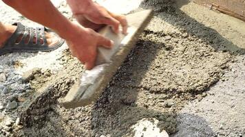 Construction, Worker Hands smooth wet cement in wooden frame at a construction site during daytime to ensure an even surface video