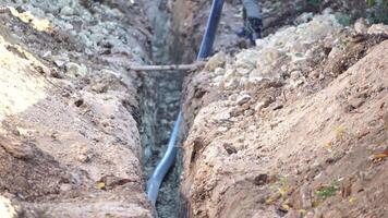 Plastic pipes laid in trenches. Workers are installing water pipeline under a city street in a trench. New pipeline in a process of building, under construction. Workers are laying pipeline. Close up video