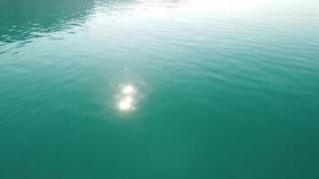 astratto aereo mare estate oceano tramonto natura sfondo. piccolo onde su acqua superficie nel movimento sfocatura con d'oro bokeh luci a partire dal sole. vacanza, vacanza e ricreativo concetto. lento movimento video