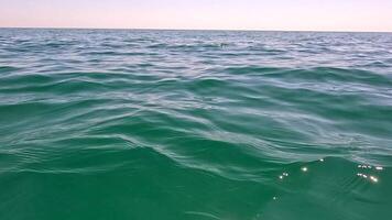 Sea water surface. Low angle view over clear azure sea water. Sun glare. Abstract nautical summer ocean nature. Holiday, vacation and travel concept. Nobody. Slow motion. Weather and climate change video