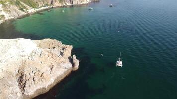 aéreo panorâmico Visão do marinha com cristal Claro azul mar e rochoso margens. iates dentro uma lindo lagoa em pano de fundo do pedras. a conceito do a ideal destino para verão viagem e período de férias. video