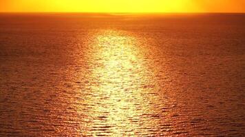 Sea water surface. Aerial view on golden sea water at sunset. Sun glare. Abstract nautical summer ocean nature. Holiday, vacation and travel concept. Nobody. Slow motion. Weather and climate change video