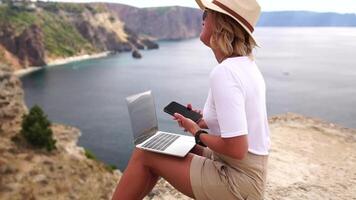 digital nomad, företag kvinna arbetssätt på bärbar dator förbi de hav. Söt lady skriver på dator förbi de hav på solnedgång, gör en företag transaktion uppkopplad från en distans. frilans, avlägsen arbete på semester video