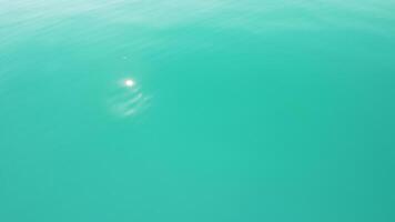 abstrakt antenn hav sommar hav solnedgång natur bakgrund. små vågor på vatten yta i rörelse fläck med gyllene bokeh lampor från Sol. Semester, semester och rekreations begrepp. långsam rörelse video