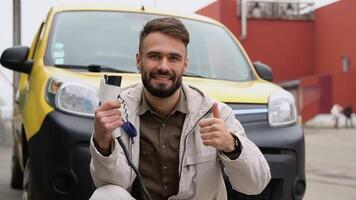 A latin man with a charger at a charging station looks into the camera video