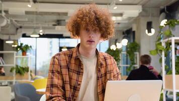 Young student freelancer in yellow shirt using laptop in coffee shop cafe working online freelance business video