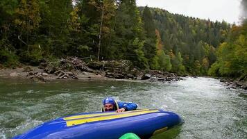 A man with an inverted kayak on a mountain river. Extreme sport video