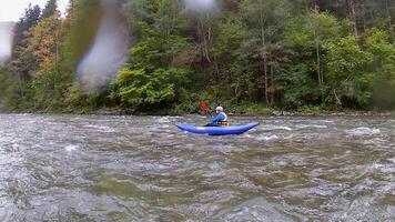 een gelukkig enthousiast mannetje in blauw opblaasbaar kano hebben een pret rijden in kalmte wateren van een rivier. extreem sport video