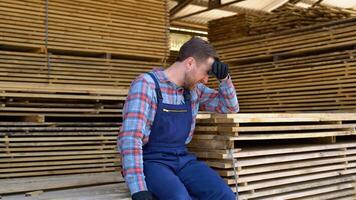 Tired young male worker in lumber warehouse video
