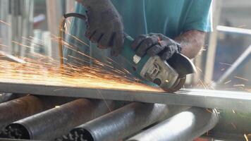 Close-up of busy welder rough grinding metal piece with rotary hand tool in workshop video