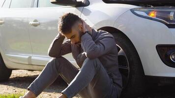 un sfortunato autista stringendo il suo testa è nel shock vicino un' rotto auto nel il mezzo di il autostrada video