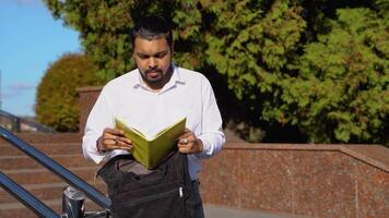 Indian student takes a book from a backpack near college video
