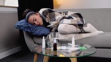 fechar acima do uma doente mulher com gripe, febre e dor de cabeça deitado embrulhado dentro uma xadrez em a sofá. período do sazonal doenças. conceito do viral doenças video