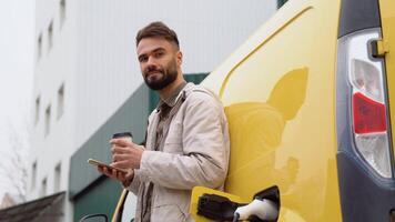 une homme avec téléphone et café à une mise en charge station regards dans le caméra video