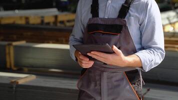 Professional heavy industry engineer worker wearing safety uniform uses tablet computer. Close up of caucasian industrial specialist standing in a metal construction manufacture video