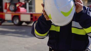 Fireman with helmet near fire engine. Concept of saving lives, heroic profession, fire safety video