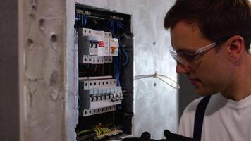 Professional electrician sets up electricity in the apartment. Electrician repairing electrical box and using screwdriver in corridor video