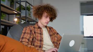 jovem ruiva homem usando computador portátil trabalhando ligar conferência com cliente dentro local de trabalho às co trabalhando espaço video