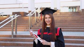 The young female specialist stands in the mantle of the master and elegantly holds the diploma video