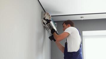 Technician man worker repairing and installs air conditioner on grey wall video
