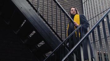 Young caucasian stylish man outside wearing coat and yellow scarf after shopping with yellow bag video