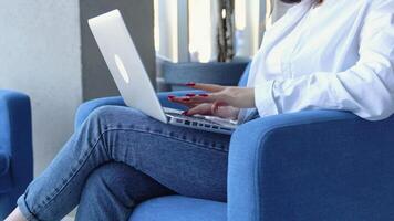 Young charming female freelancer using laptop computer for distance job while sitting in modern coffee shop interior. Close up of hands video