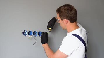 Professional electrician technician installing a wall socket in a new house. Electrician mounting wiring for electric sockets video