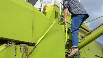 bestuurder Gaan combineren cabine Bij zonsondergang. professioneel agronoom werken Aan oogsten herfst campagne. niet herkend boer operator krijgen in oogstmachine inspecteren machine. agribusiness arbeider concept video