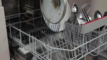 Filling dirty dishes in the dishwasher. Close up, 4K video