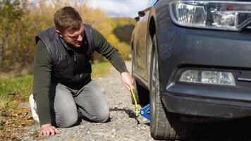 man hissar bil på domkraft till byta ut punkterad däck. ersättning av punkterad däck på väg. hjälp video