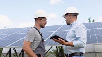 zwei Arbeitskräfte im Helme prüfen das Eingerichtet Solar- Tafeln. Grün Elektrizität und Alternative Energie ökologisch Konzept video