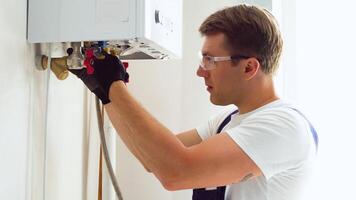 Closeup of plumber using wrench while fixing boiler or water heater, working on heating system in apartment video