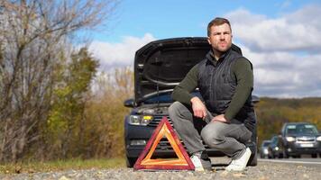 frustré homme sur route avec cassé auto. côté avertissement Triangle, avertissement approche circulation de une cassé vers le bas voiture video