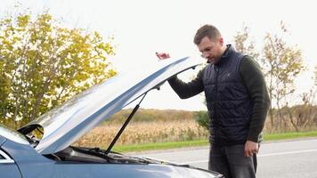 frustrato uomo riparazione incidente macchina. triste deluso uomo su rotto auto. veicolo dai un'occhiata motore danno guai. auto motore video