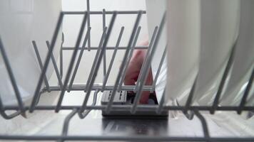 A man's hand puts a dishwasher pill in a close-up dishwasher in the kitchen video