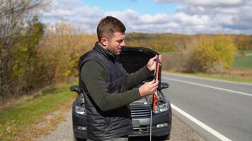 giovane uomo preparazione un' rosso triangolo per avvisare altro strada utenti, auto abbattersi o motore fallimento fermare a campagna strada video