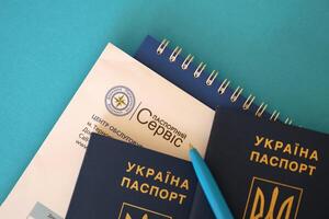 KYIV, UKRAINE - NOVEMBER 27, 2023 Passport service logo with international ukrainian passport and pen photo