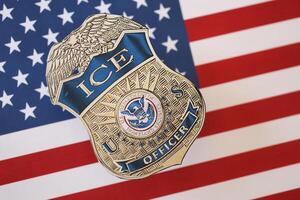 KYIV, UKRAINE - MARCH 9, 2024 US ICE Officer badge on United States of America flag photo