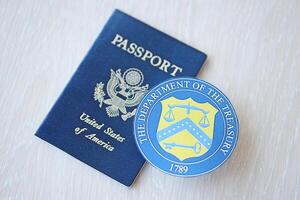 KYIV, UKRAINE - MARCH 9, 2024 US The Department of the Treasury seal and United States passport on wooden table photo