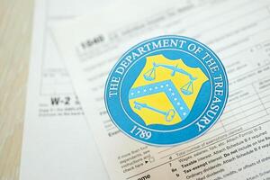 KYIV, UKRAINE - MARCH 9, 2024 US The Department of the Treasury seal on 1040 and W-2 IRS tax forms photo