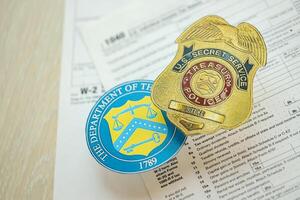 KYIV, UKRAINE - MARCH 9, 2024 US Treasury Police Secret Service Officer badge and Department of Treasury seal on 1040 and W-2 IRS tax forms photo