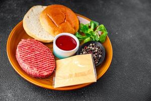 hamburguesa conjunto crudo chuleta, bollo, queso, tomate salsa, verduras Fresco Cocinando aperitivo comida comida bocadillo en el mesa Copiar espacio comida antecedentes rústico foto