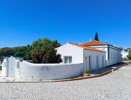A white house with a red tiled roof located in a Mediterranean region. photo