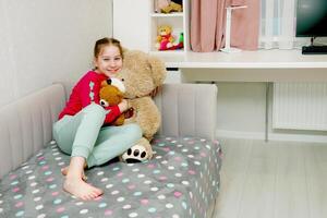 happy girl at home on bed hugging soft teddy bear toys photo