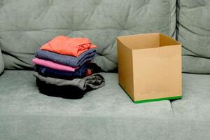 doblada ropa siguiente a un vacío caja en el sofá foto
